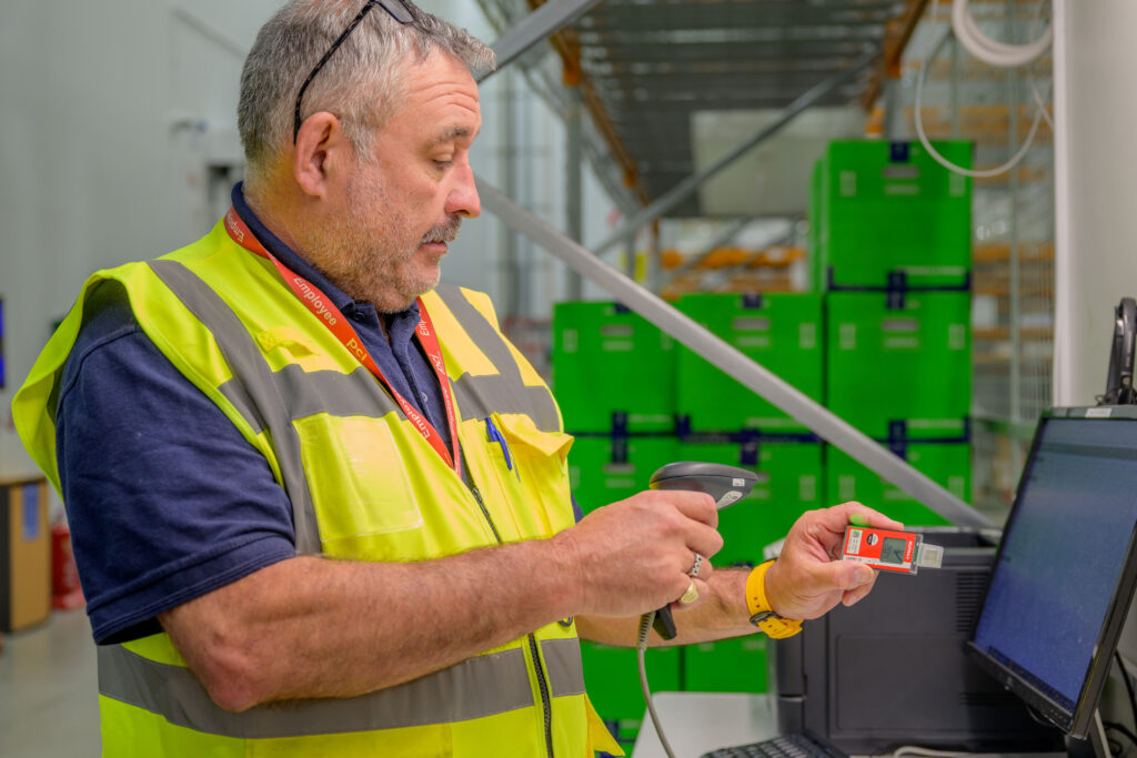 PCI Pharma employee scanning shipment barcode in a clinical logistics warehouse, ensuring temperature-controlled accuracy for clinical supply management.